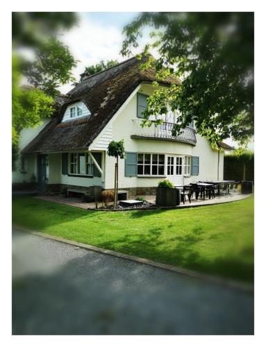a white house with a thatched roof at Bed & Bokes aan de Maaskant in Lanaken