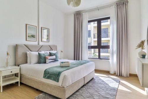 ein weißes Schlafzimmer mit einem großen Bett und einem Fenster in der Unterkunft HiGuests - Stylish Apt With Stunning Beach Views and Pools in Dubai