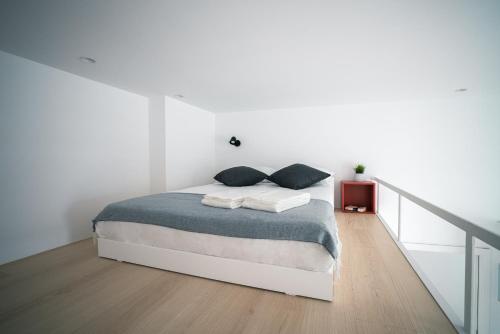a white bedroom with a bed and a staircase at PORTARIA HOUSING in Aveiro