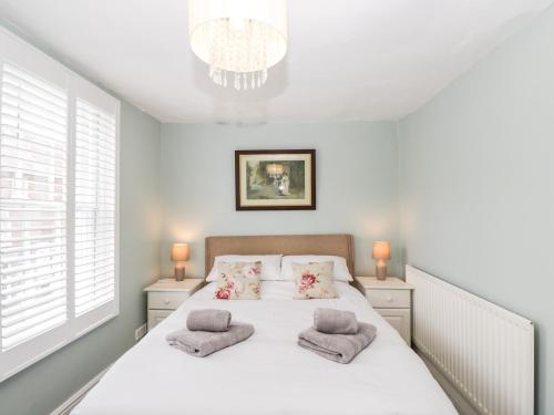 a bedroom with a white bed with two pillows at Cuckoo Cottage in Worcester