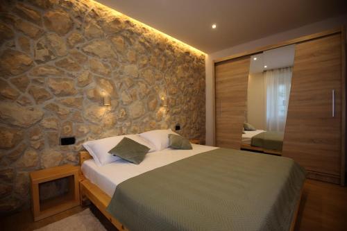 a bedroom with a bed with a stone wall at Villa Fani in Rijeka