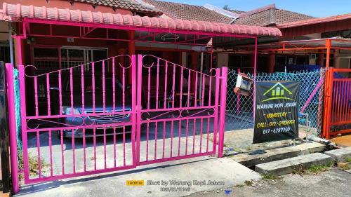 a pink gate in front of a house with a sign at Homestay d' Tengah Bandar Kuala Rompin in Kuala Rompin