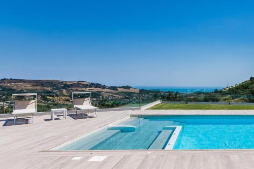 a swimming pool with chairs and a view of the ocean at Villa Lerant in Acquaviva Picena