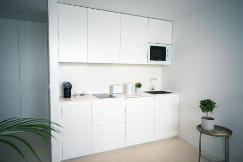 a white kitchen with a sink and a microwave at PORTARIA HOUSING in Aveiro