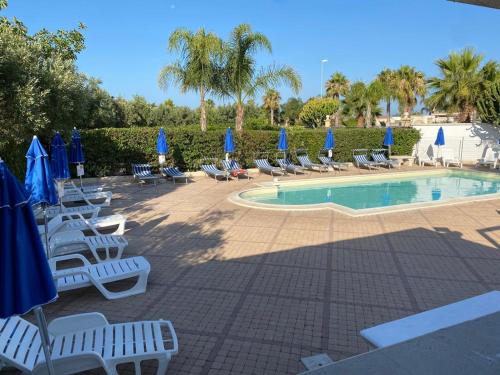 un grupo de sillas y sombrillas junto a una piscina en Akramar Village, en San Leone