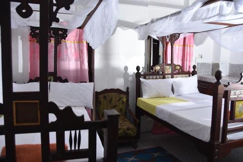 a bedroom with two beds and a canopy bed at BABAbora house in Ngambo