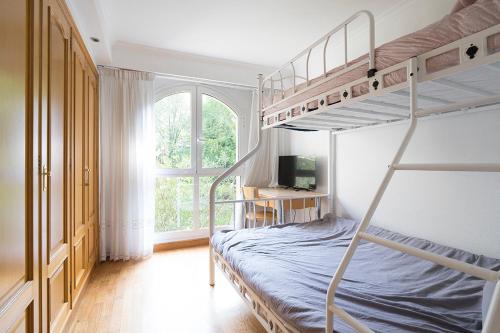 ein Schlafzimmer mit zwei Etagenbetten und einem Fenster in der Unterkunft NEW Apartment & Terrace. Steps to Ondarreta Beach in Añorga-Lugariz