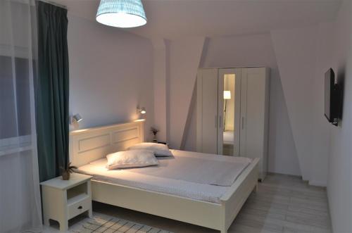 Dormitorio blanco con cama con espejo en Casa Calin, en Crisan