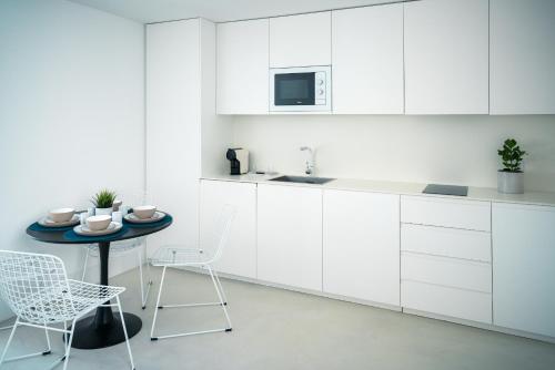 a kitchen with white cabinets and a table and chairs at PORTARIA HOUSING in Aveiro
