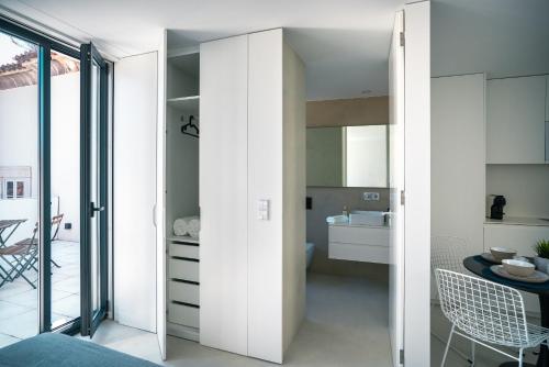 a kitchen with white cabinets and a dining room at PORTARIA HOUSING in Aveiro