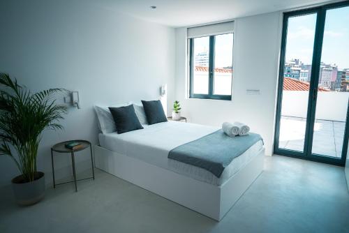 a white bedroom with a bed and a large window at PORTARIA HOUSING in Aveiro