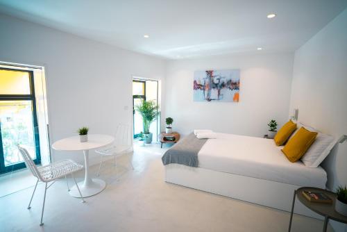 a white bedroom with a bed and a table and chairs at PORTARIA HOUSING in Aveiro