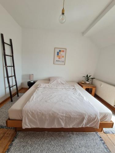 a white bed in a room with a ladder at Geschmackvolle Wohnung im Herzen von Sinzig in Sinzig