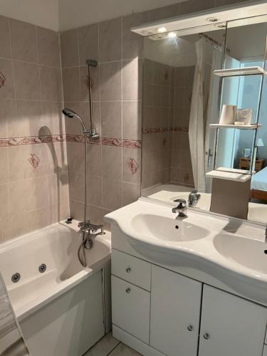 uma casa de banho com um lavatório, um espelho e uma banheira em La Chaumiere em Agde