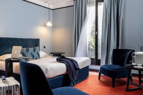 um quarto de hotel com uma cama, uma secretária e cadeiras em L'Hôtel em Nantes