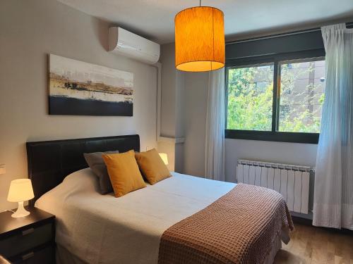 um quarto com uma cama com almofadas amarelas e uma janela em Apartamento familiar em Madrid