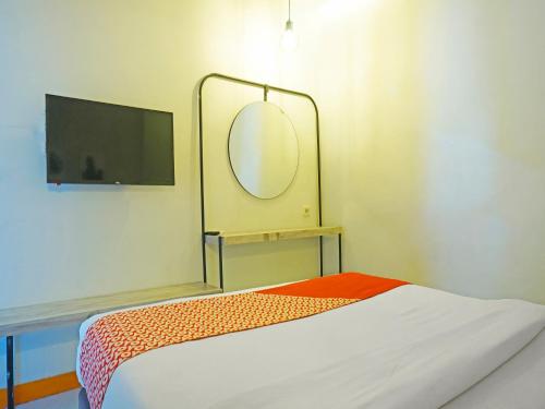 a room with a bed with a mirror and a tv at OYO 91455 New Hotelo in Jakarta