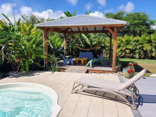 un gazebo e una sedia accanto a una piscina di Villa Ohana a Sainte-Anne