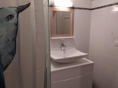 Baño blanco con lavabo y espejo en Gîtes Merour - Telgruc, en Telgruc-sur-Mer