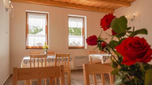 comedor con mesa, sillas y rosas rojas en Zempléni Tündérkert vendégház en Füzérkomlós