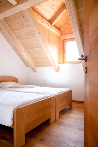 a bed in a room with a wooden ceiling at Apartma Mlekuž in Bovec