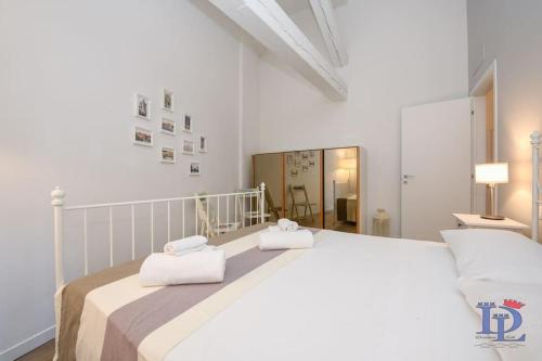 a white bedroom with a large bed with towels on it at Desenzanoloft Peler in Desenzano del Garda