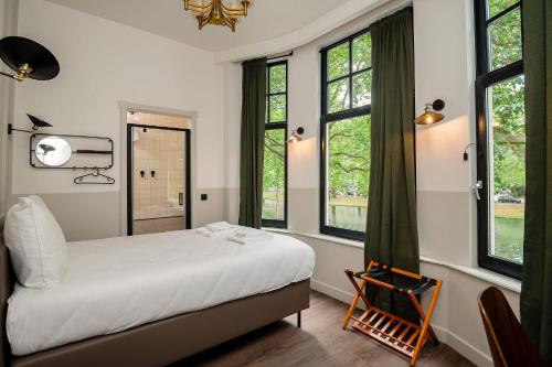 una camera con letto, finestre e sedia di Mr.Lewis Rotterdam a Rotterdam