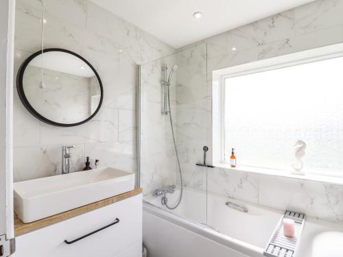 a bathroom with a sink and a tub and a mirror at Island House in Colchester