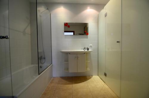 biała łazienka z umywalką i prysznicem w obiekcie Trias Plaza w mieście Pals