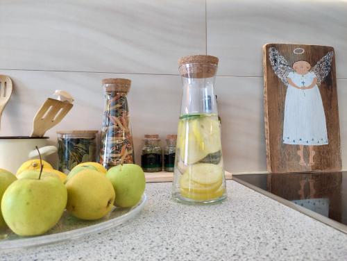 a plate of apples on a counter with a bottle of lemon juice at Apartament MAZI w centrum PRIMORE in Gdańsk