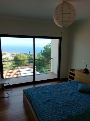 a bedroom with a blue bed and a large window at Ponta do Sol Amazing 3 Bedroom Apartment in Ponta do Sol