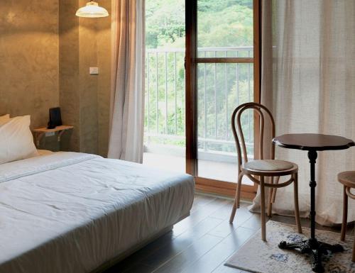a bedroom with a bed and a table and a window at Seaside Snooze in Xiaoliuqiu