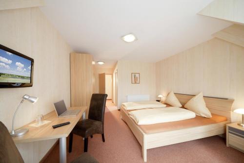 une chambre avec un lit et un bureau avec un ordinateur portable dans l'établissement Pension am Schlossberg, à Reichenberg