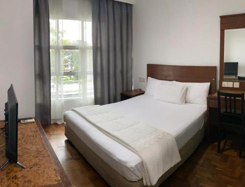 een slaapkamer met een groot bed en een televisie bij EE HOTEL Johor Jaya in Johor Bahru