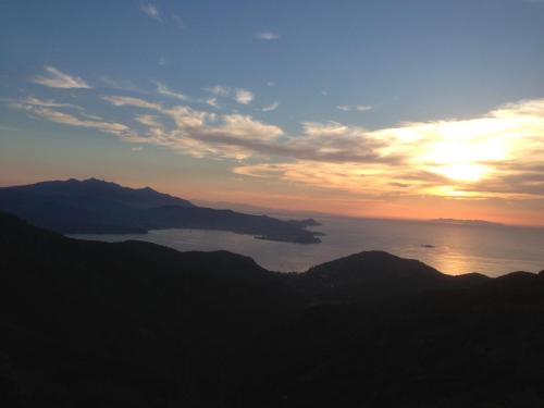 a sunset over the ocean with mountains in the background at Hotel Acquamarina in Portoferraio