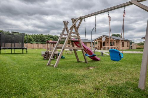 a playground with a slide and swings in a yard at Osada Trzy Siostry in Pobierowo