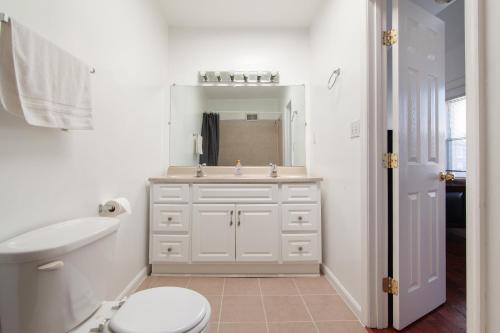 Baño blanco con aseo y lavamanos en Spacious, Relaxing, 4 Bd 3.5 Ba Home In Petworth! en Washington