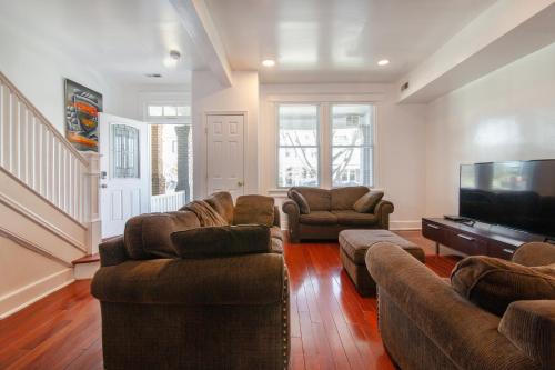 a living room with couches and a flat screen tv at Spacious, Relaxing, 4 Bd 3.5 Ba Home In Petworth! in Washington, D.C.