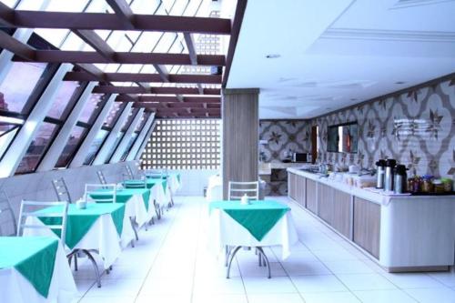 a restaurant with green and white tables and a counter at Hotel Nacional in Arapiraca