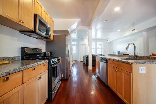 a large kitchen with wooden cabinets and a sink at Spacious, Relaxing, 4 Bd 3.5 Ba Home In Petworth! in Washington, D.C.