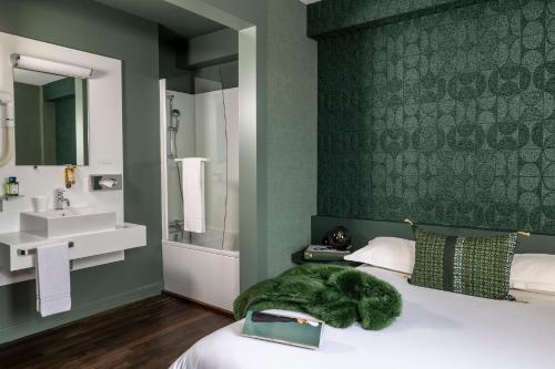 a bedroom with a bed with a green wall at L'Hôtel in Nantes