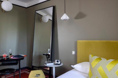 a bedroom with a mirror and a bed with a yellow headboard at L'Hôtel in Nantes