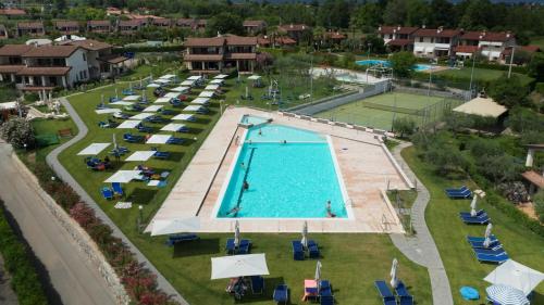 uma vista superior para uma piscina com cadeiras e um campo de ténis em Residence Primera em Moniga