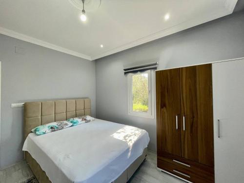 - une chambre avec un grand lit et une armoire en bois dans l'établissement Avci Villa-Fethiye 3+1 in Garden with Private Pool, 10 minutes to the beach, à Fethiye