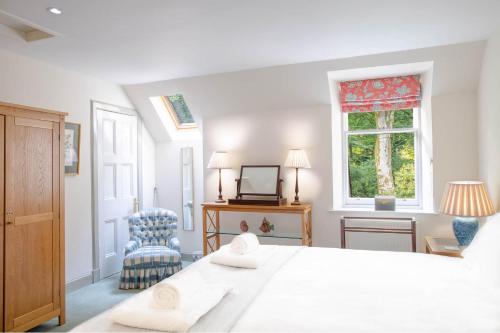 道格拉斯城堡的住宿－The Stables，白色的卧室设有一张大床和一个窗户