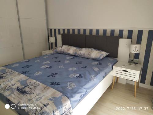 a bed with a blue comforter and a night stand at Azzurro Sarafovo in Burgas City