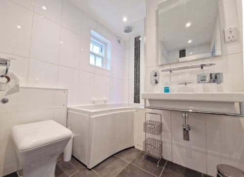 a white bathroom with a toilet and a tub and a sink at Beech Apartment in Bowness-on-Windermere
