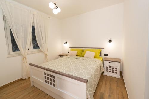 um quarto branco com uma cama grande e almofadas amarelas em Modern apartment with swimming pool em Kaštela