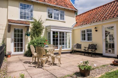 a patio with chairs and a table in front of a house at Farmhouse Cottage at Mollett's Farm in Saxmundham