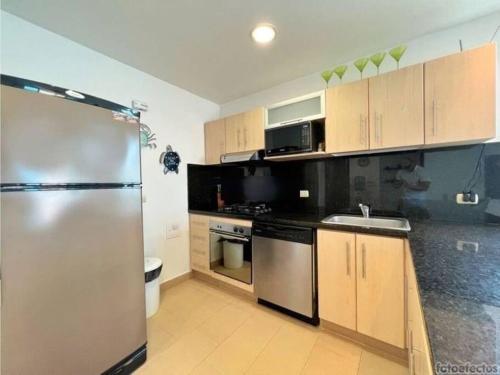 a kitchen with wooden cabinets and a stainless steel refrigerator at Casa Arcoíris: Espectacular casa en Cartagena con Acceso directo a la Playa in Cartagena de Indias